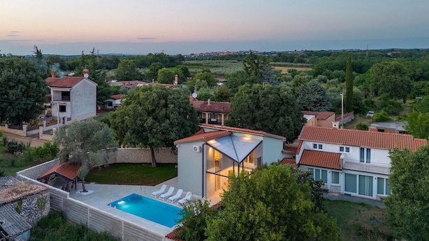 A residential area with a swimming pool, houses with red-tiled roofs, and a view of the sea in the background. - Villa Pietra Cattunara (Brtonigla)