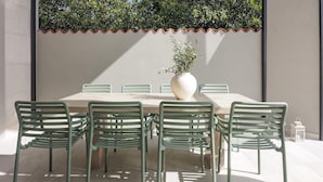 A dining area with a table and chairs, a potted plant, and a tiled wall. - Villa Pietra Cattunara (Brtonigla)
