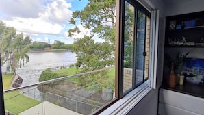 Ein Zimmer mit großem Fenster und Blick auf einen Fluss und Grünflächen.