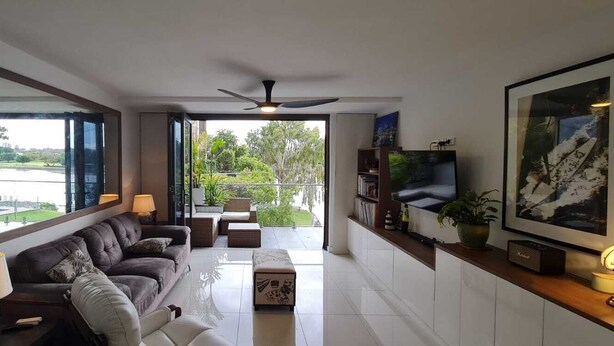 Ein modernes Wohnzimmer mit einer Couch, einem Couchtisch und einem Fernseher auf einem Holzregal.