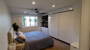 Ein Schlafzimmer mit Bett, Fenster, Deckenventilator und Kleiderschrank.