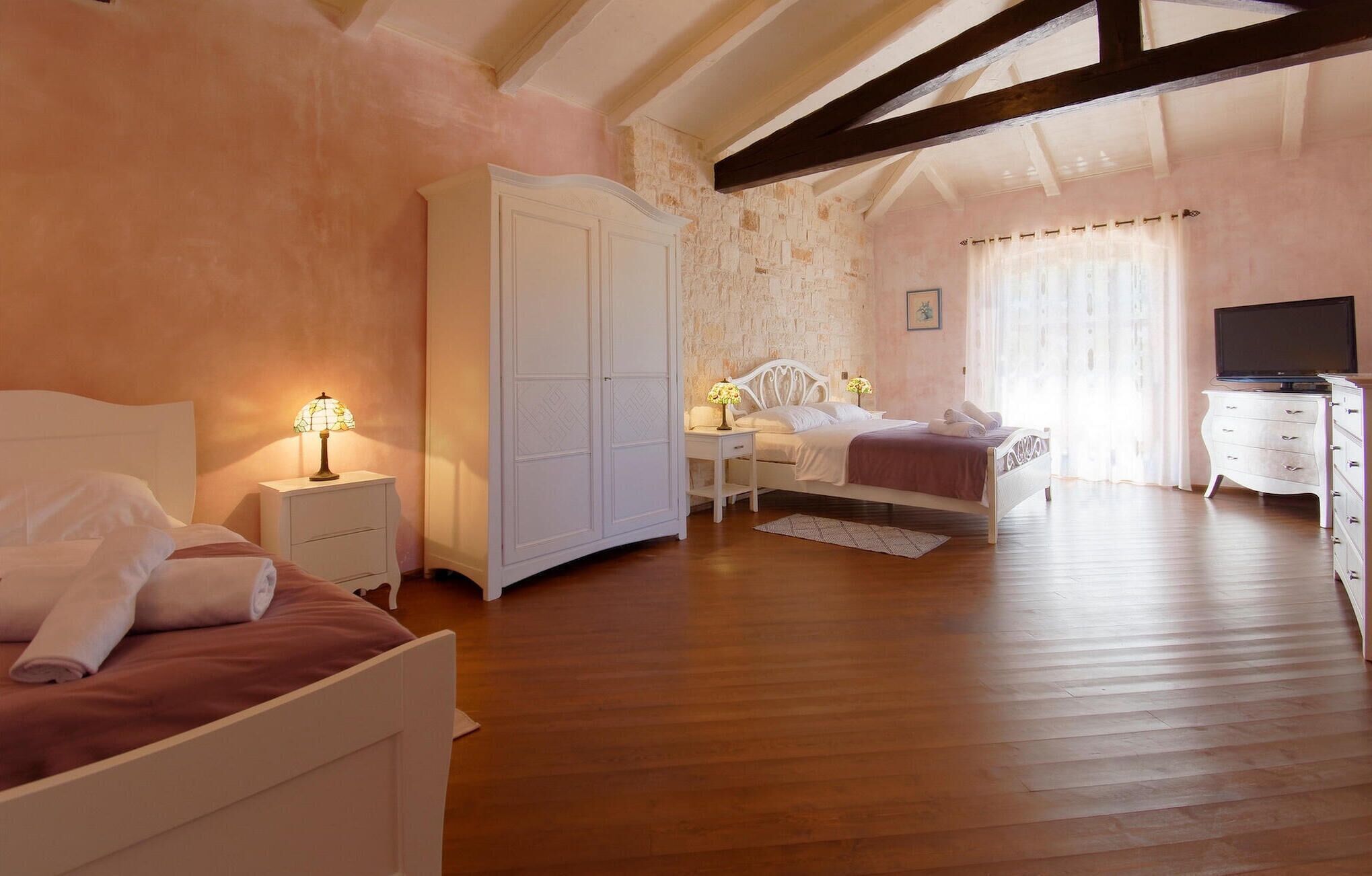 Ein Schlafzimmer mit zwei Betten, einem Kleiderschrank, einem Fernseher und einer Steinwand.