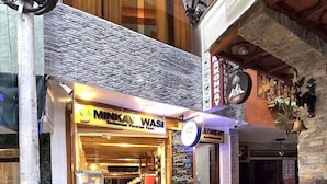 A restaurant named MINKAY WASI with a signboard, outdoor seating, and potted plants. - Amakonkay Machupicchu (Machu Picchu)