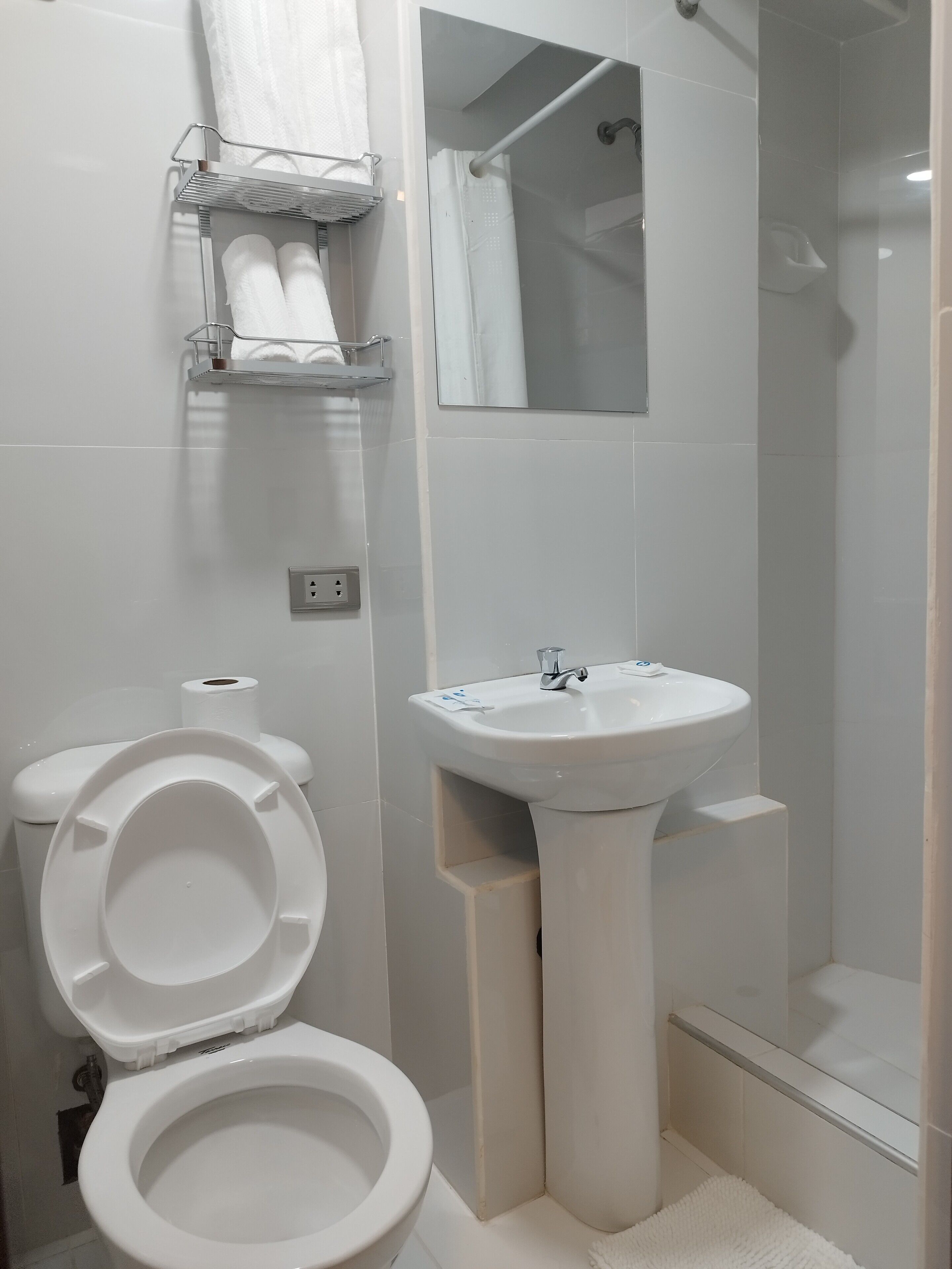 Een moderne badkamer met toilet, wastafel en douche.