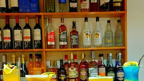 A bar with various liquor bottles on shelves and three cocktails on the counter. - Amakonkay Machupicchu (Machu Picchu)