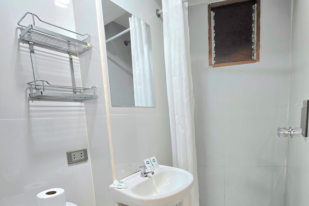 A modern bathroom with a toilet, sink, shower, and a mirror.