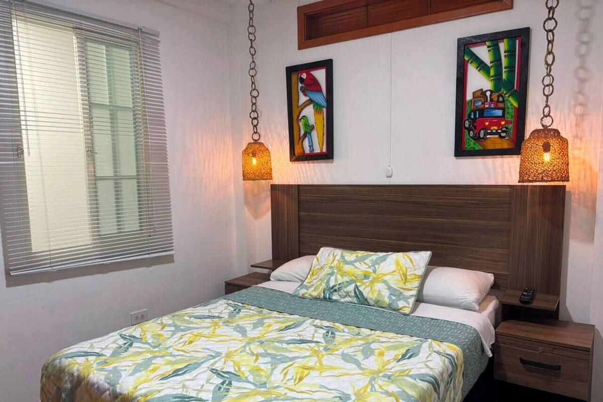 Une chambre à coucher comprenant un lit, deux tables de chevet, une tête de lit en bois et des œuvres d’art murales.