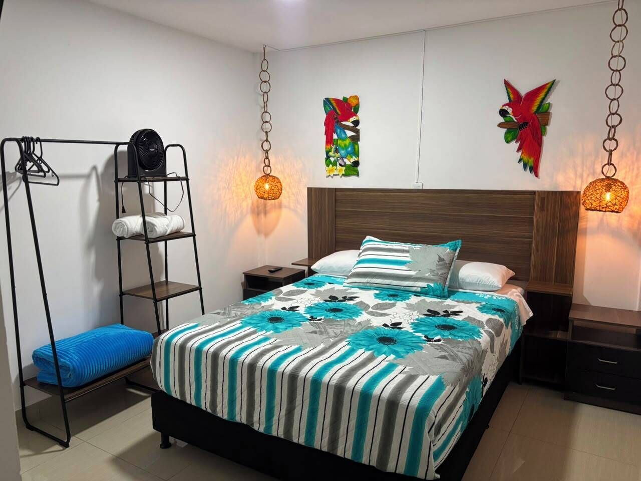 A bedroom with a bed, a hanging chair, and two wall-mounted lamps.