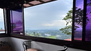 Una habitación con dos taburetes y un ventanal que ofrece vistas a un paisaje verde y colinas distantes.