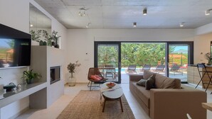 Un salon moderne doté d’un téléviseur à écran plat, d’un canapé, d’une table basse et d’une grande fenêtre donnant sur un espace piscine.