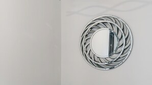 En modern inredning med en spiralformad väggdekoration i metall, en krukväxt och ett minimalistiskt trappräcke.