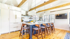 A spacious kitchen with white cabinets, a large island, and wooden bar stools. - Renovated kitchen less than 2 miles to beach, walk to restaurants & bike trail (Harwich)