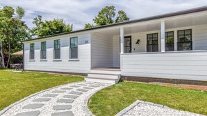A modern single-story house with a covered porch, a stone pathway leading to the entrance, and a brick foundation. - Renovated kitchen less than 2 miles to beach, walk to restaurants & bike trail (Harwich)