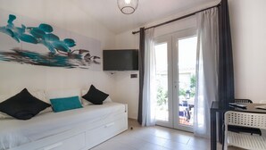 Ein modernes Zimmer mit einem weißen Sofa, einem Flachbildfernseher und einer Schiebetür zu einem Außenbereich.