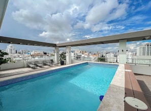 A rooftop pool with a city view, lounge chairs, and a potted plant. - Goistay Elegant Refugio Caribeño 1br Gym Pool Naco APT 9F (Santo Domingo)