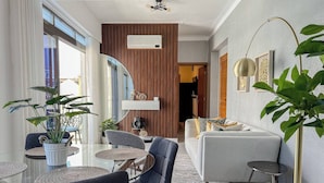 Un salon moderne comprenant un canapé, des fauteuils, une table basse et un coin repas avec une table et des chaises.