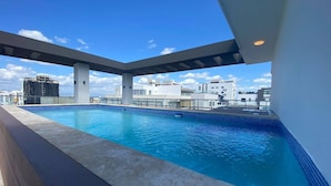 Une piscine sur le toit offrant une vue sur les bâtiments environnants.