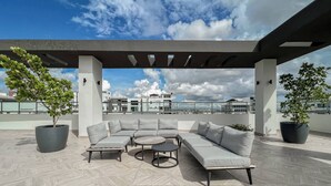 Une terrasse sur le toit aménagée avec un canapé d’angle, une table ronde et des plantes en pot.