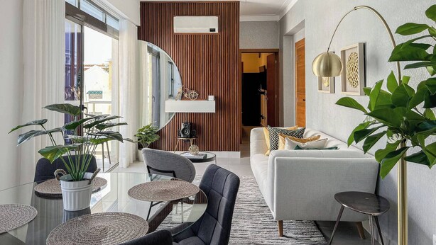Un salon moderne comprenant un canapé, des fauteuils, une table basse et un coin repas avec une table et des chaises en verre.