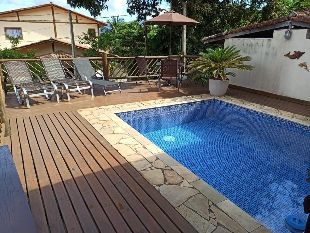 A swimming pool with a tiled deck, lounge chairs, and a potted plant.