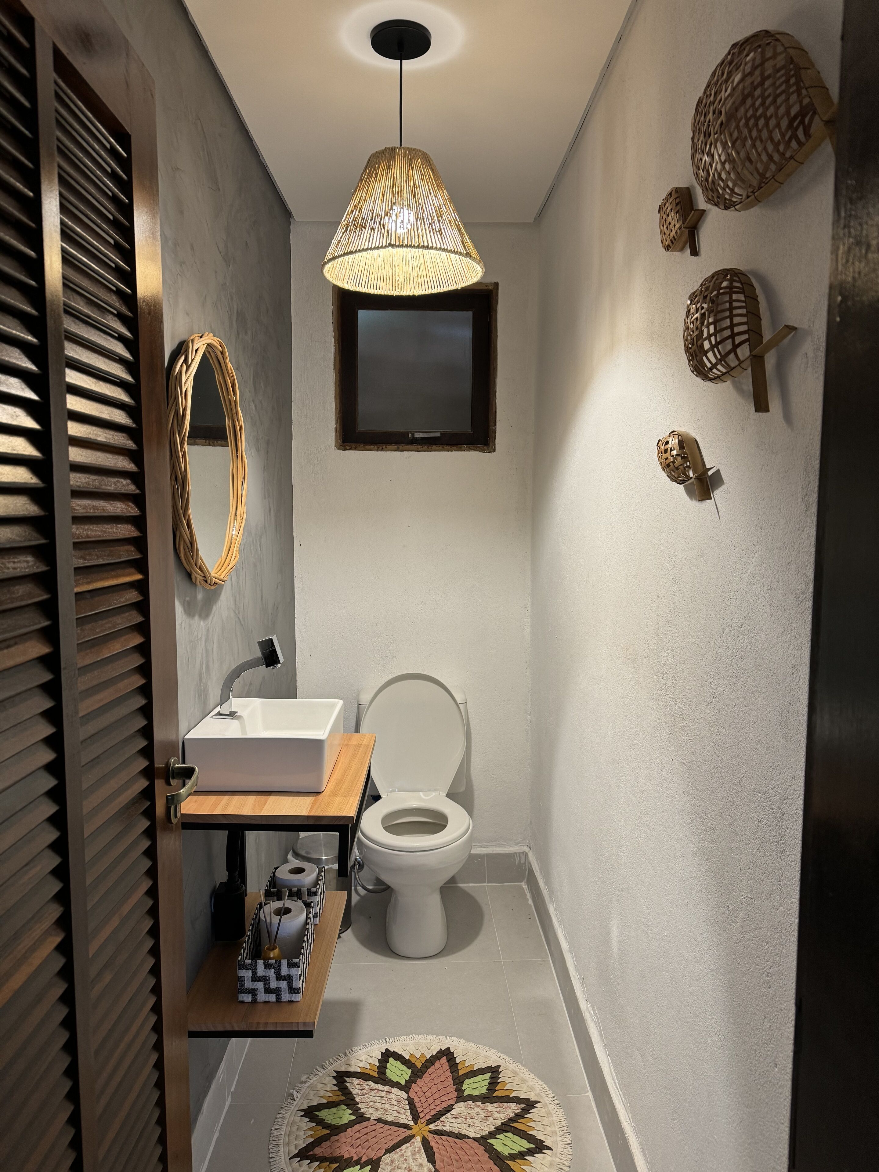 A compact bathroom with a modern design, featuring a toilet, sink, and decorative wall-mounted items.