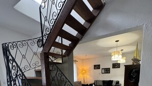 A modern interior with a wooden staircase, a dining area, and a living room. - Sobrado a 700 Metros Praia do Veloso (São Pedro Ilhabela)
