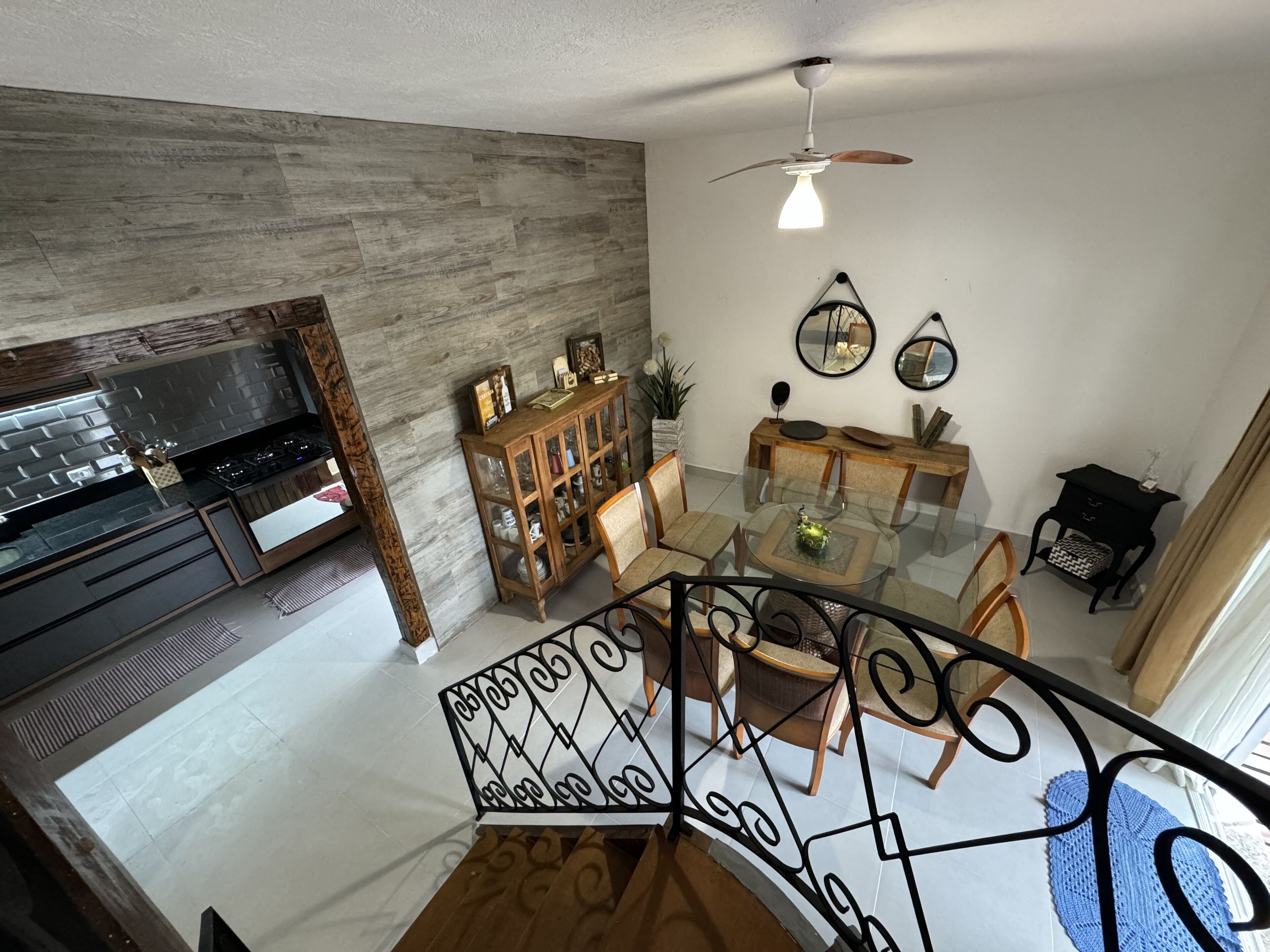 A modern living room with a dining area, a kitchen, and a staircase.
