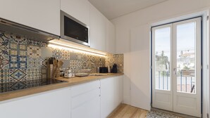 A modern kitchen with patterned backsplash tiles, a microwave, and a wooden countertop. - S. Bento Downtown Apt (Oporto)