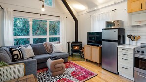 Una sala de estar acogedora con chimenea, televisor y una zona de cocina con electrodomésticos modernos.