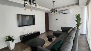 A modern living room with a flat-screen TV, a black sofa, a coffee table, and a potted plant. - Depa Asoluta, Cerquita de TODO en el Norte de Mérida. CoWorking (Mérida)