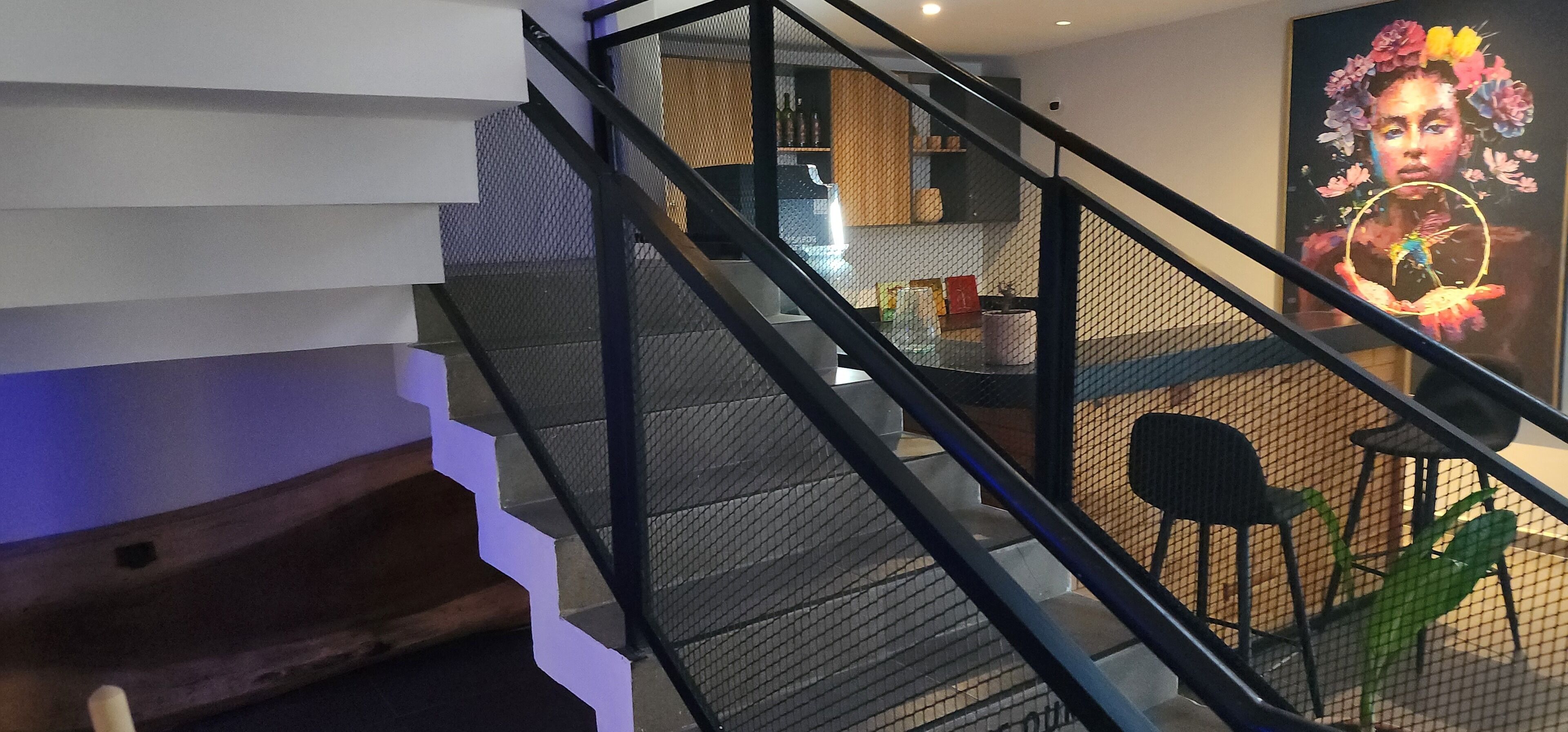 Un escalier moderne avec une rampe en treillis menant à un espace repas.