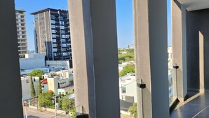 A view from a balcony with a clear sky, featuring modern buildings, a street, and some greenery. - Depa Asoluta, Cerquita de TODO en el Norte de Mérida. CoWorking (Mérida)