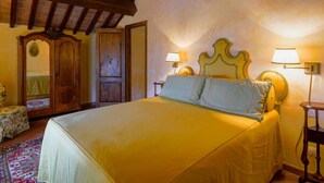 A bedroom with a large bed, wooden ceiling beams, a wardrobe, and two bedside lamps. - La Vista by Interhome (Vicchio)