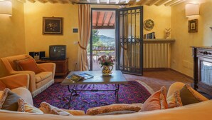 A cozy living room with a sofa, a coffee table, and a TV. There is a view of a balcony with outdoor furniture. - La Vista by Interhome (Vicchio)