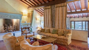 A spacious living room with a fireplace, a sofa set, and a large window with curtains. - La Terrazza by Interhome (Vicchio)