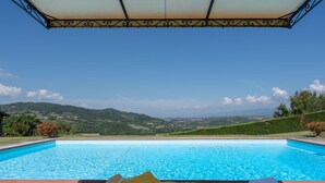 A poolside area with lounge chairs and a view of a mountainous landscape. - La Terrazza by Interhome (Vicchio)