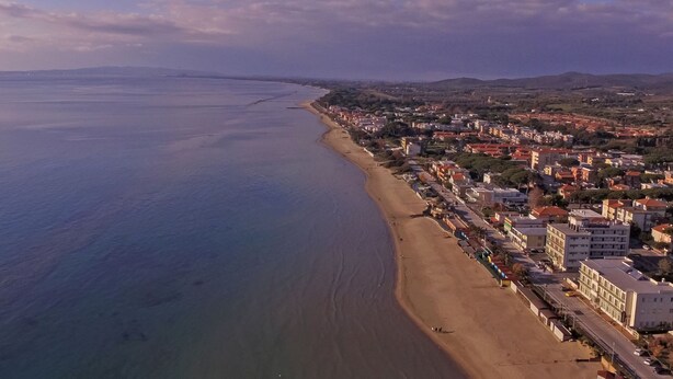 An aerial view of a coastal town with a long sandy beach, residential buildings, and a clear view of the sea. - Apartment Angela by Interhome (Follonica)