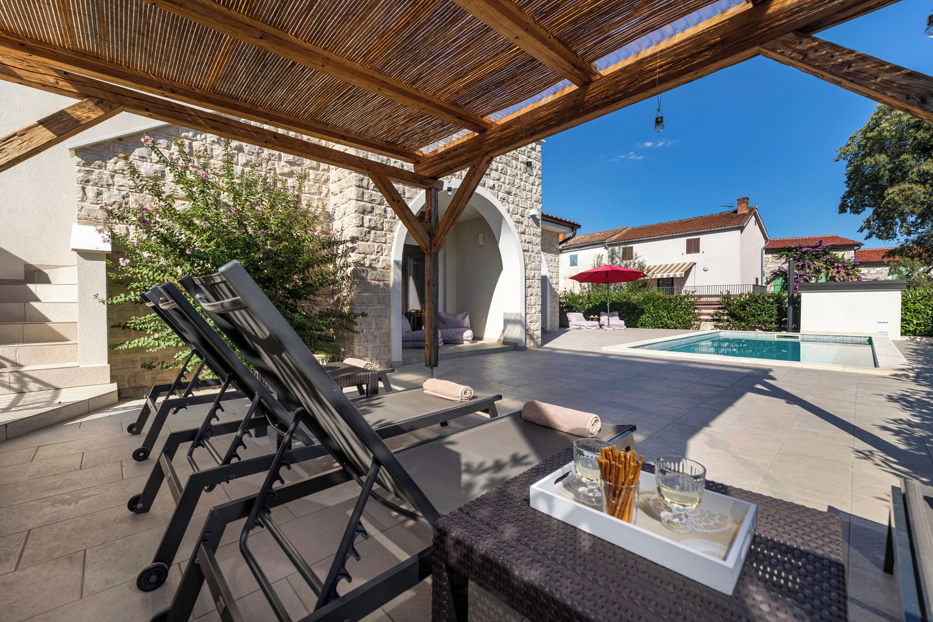 Une terrasse extérieure avec une piscine, des chaises longues et une table sur laquelle se trouve un plateau de collations.