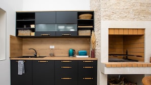 A compact kitchen with black cabinets, a wooden countertop, and a stone wall.