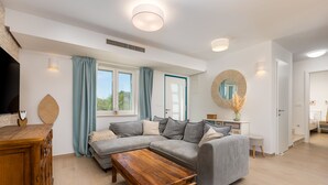 A modern living room with a grey sofa, wooden coffee table, and a large mirror.