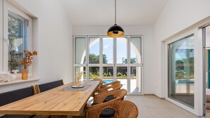 A dining area with a wooden table, wicker chairs, and a black pendant light.