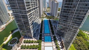 Un edificio alto con una piscina central rodeada de follaje y otros edificios.
