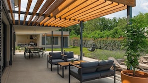 A modern outdoor patio with wooden pergola, seating, and a small kitchen area. - Awesome home in Vizinada (Vizinada)