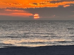 A beach with the ocean and a sunset.