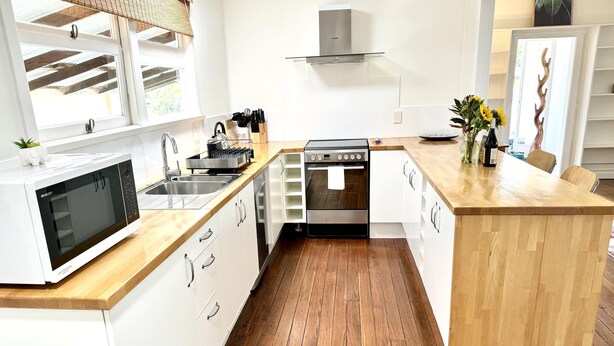 Una cocina moderna con armarios blancos, encimera de madera, horno empotrado y microondas.