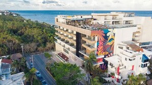 A modern hotel with multiple floors, balconies, and a vibrant mural on one side.