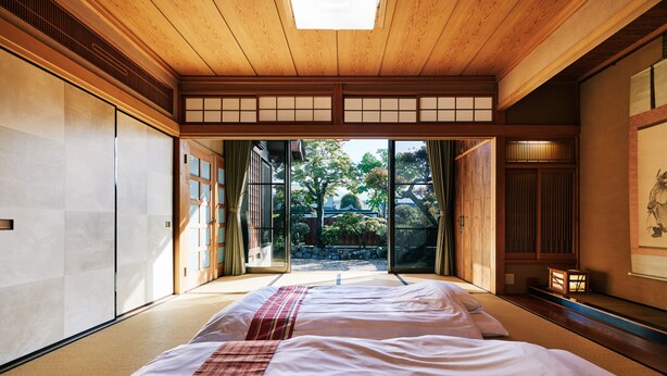 A traditional Japanese-style room with tatami flooring, sliding doors, and a view of a garden. - Machi-jyu  (Chichibu)