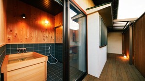 A wooden interior with a glass-enclosed shower area, a wooden bathtub, and a tiled floor. - Machi-jyu  (Chichibu)