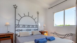 A bedroom with a bed, bedside tables, a window, and a decorative metal headboard. - Port Pals family terrace & garden by Interhome (Pals)
