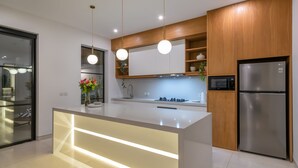 Une cuisine moderne dotée d’un îlot central, de meubles en bois, d’appareils électroménagers en acier inoxydable et de luminaires suspendus.